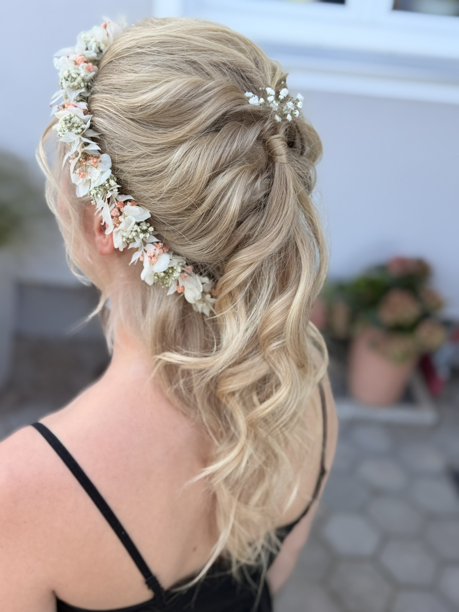 Brautstyling: blonde Hochsteckfrisur mit Blütenkranz und offenen Wellen