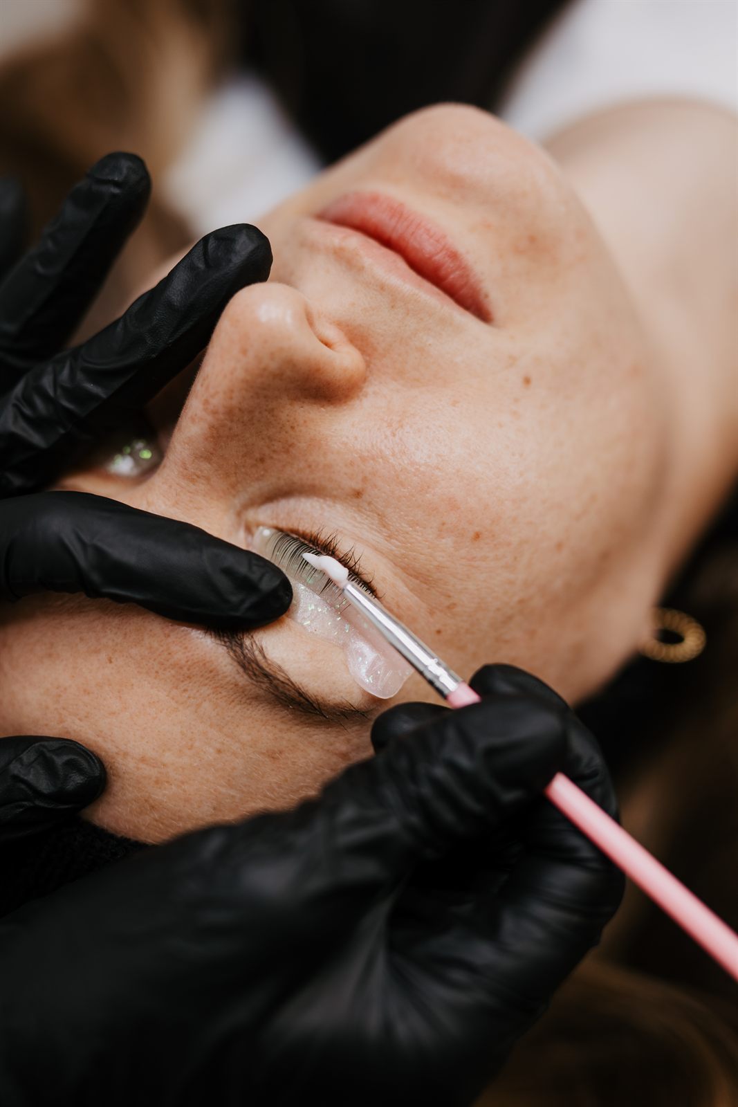 Pflege wird beim Wimpernlifting mit dem Pinsel auf die Wimpern gestrichen