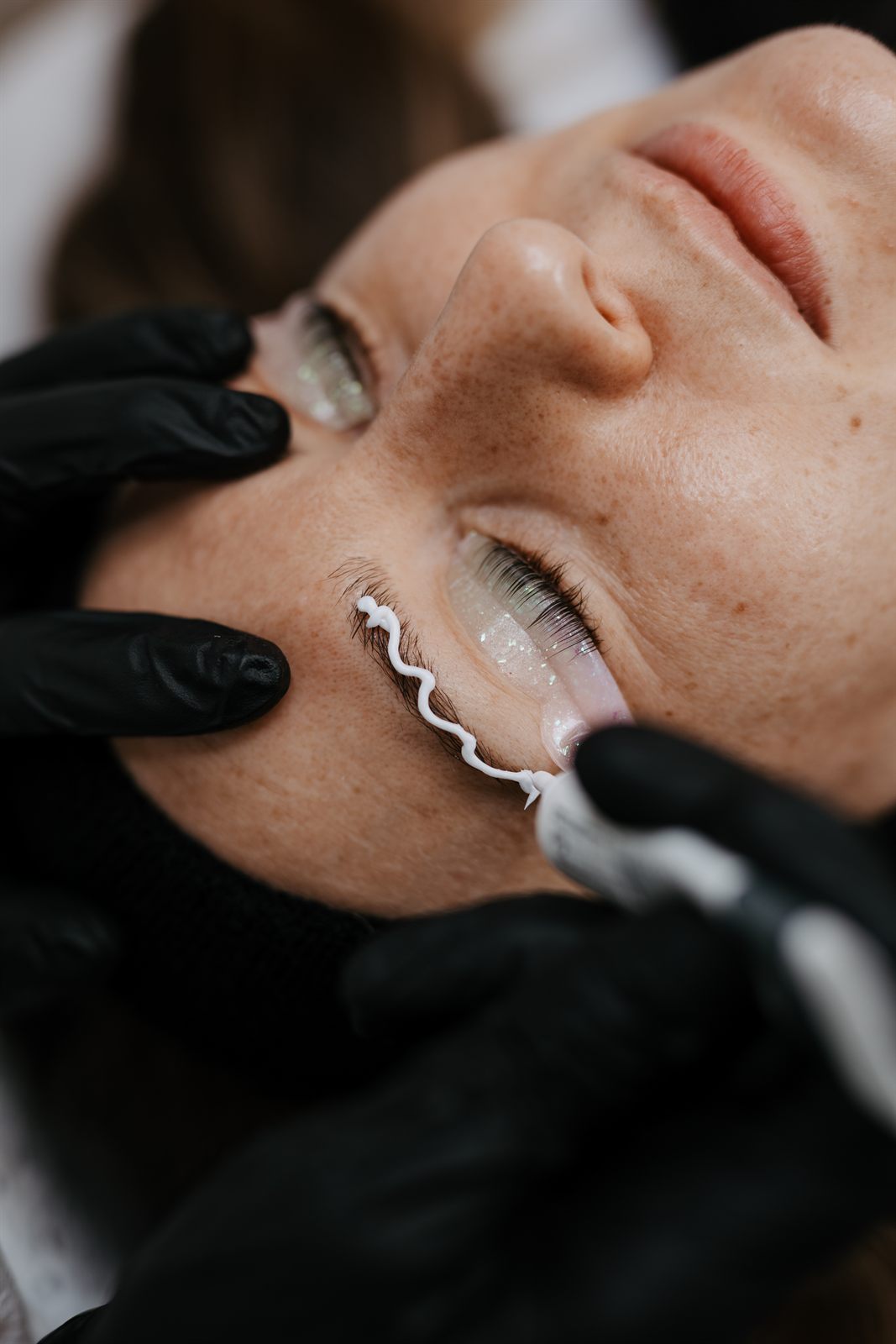 Brauenfarbe wird beim Browlifting in einer Wellenlinie entlang der Braue aufgetragen