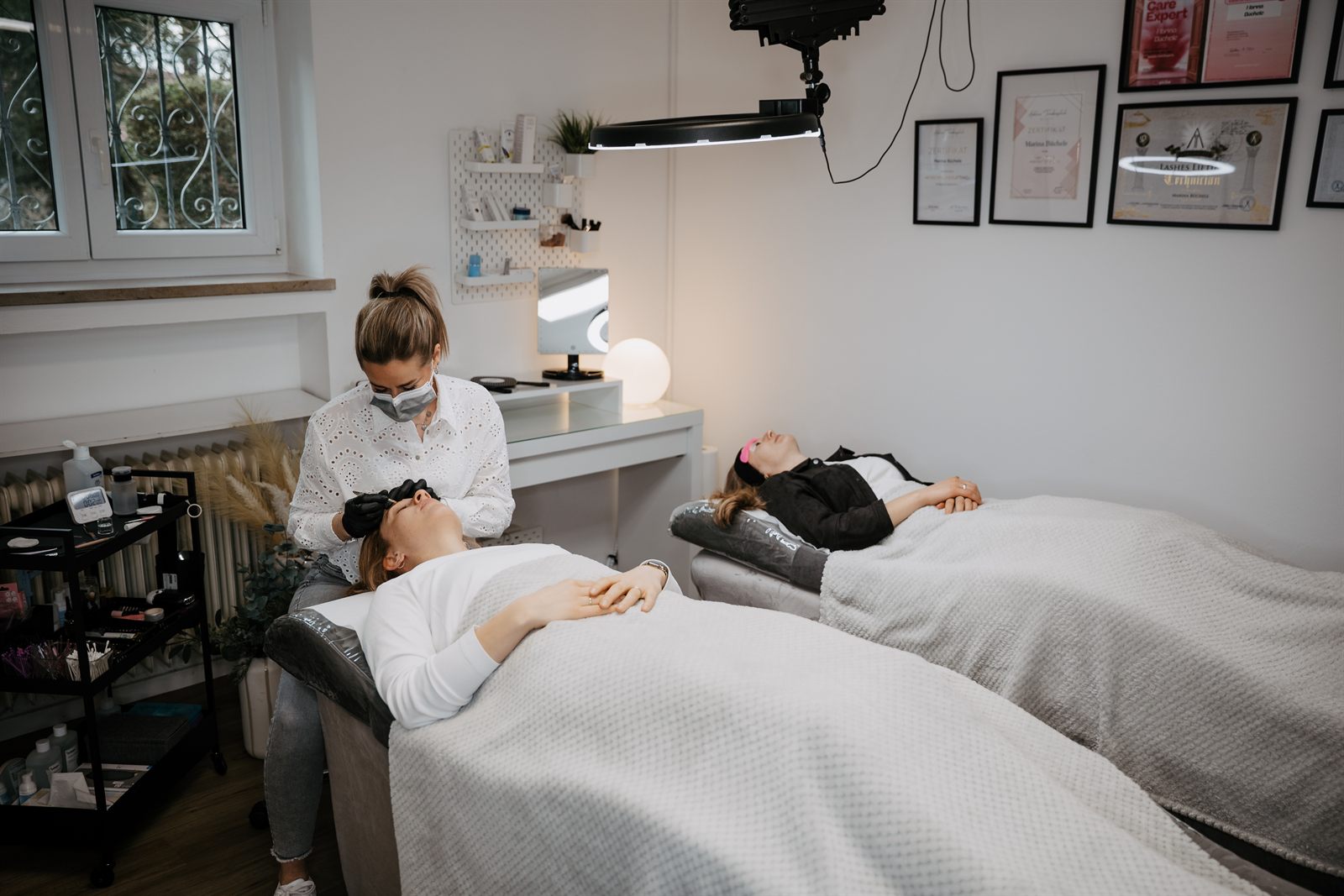 Marina behandelt eine Kundin beim Wimpernlifting, unter der Lampe liegt eine zweite